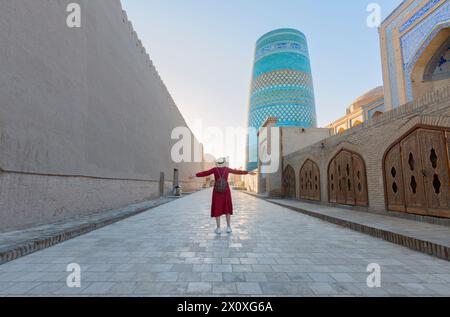 Giovane donna che scatta una foto degli edifici orientali nell'antica città di Itchan Kala. Khiva, Uzbekistan Foto Stock