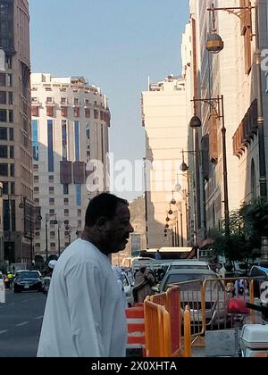 Un uomo arabo che passa sul lato della strada a Medina durante il giorno Foto Stock