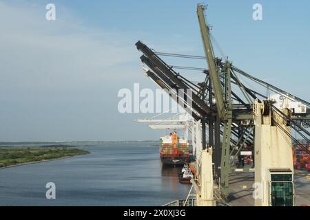 Nave portacontainer con gru durante le operazioni di carico carico carico e scarico mediante gru a cavalletto azionate da stevedores. Foto Stock