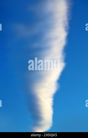 Il sentiero di un aereo (contrail) nel cielo, disorientato da un forte vento, come una nuvola Foto Stock