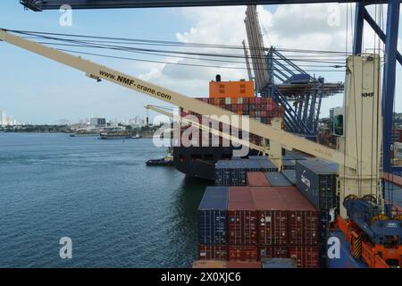 Nave portacontainer dotata di gru durante le operazioni di carico carico carico e scarico mediante gru a cavalletto azionate da stevedores. Foto Stock