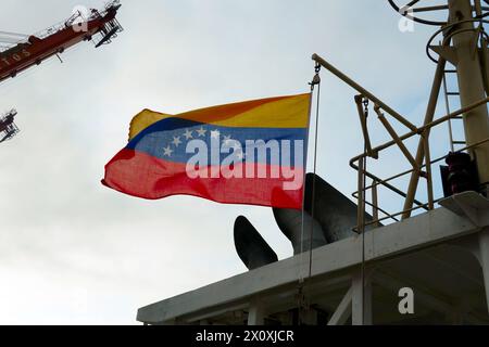 La bandiera del Venezuela vola sul vento e appesa all'albero di navigazione vicino ai tubi di scarico dell'imbuto sulla nave mercantile. Foto Stock