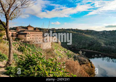 Vecchio edificio con finestre e tetti marroni sulla cima della collina, fiume Tago tra montagne rocciose, cielo blu con nuvole bianche sullo sfondo, visto dal panorama Foto Stock