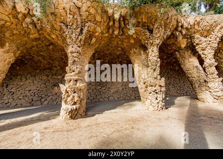 Viadotto in sala lavanderia Portico con colonne in muratura con parete in pietra sullo sfondo nel Parc Guell, opera architettonica di Gaudí, giorno di sole a Ba Foto Stock