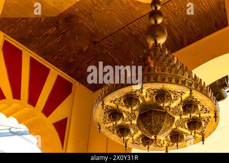 Lampada in bronzo in stile arabo o marocchino appesa al soffitto, replica dell'edificio della moschea di Cordova, pareti gialle e ingresso ad arco con decorazioni rosse Foto Stock