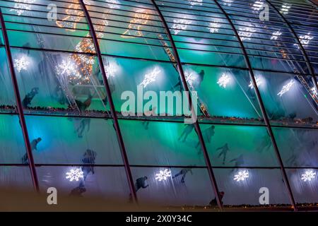 Vista aerea del tetto trasparente su una pista di pattinaggio su ghiaccio con lampade decorative, persone che pattinano nella tranquilla notte di dicembre al Mercatino di Natale di Maastri Foto Stock