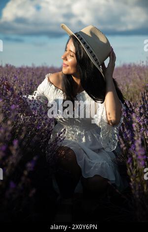 Bella giovane donna che ammira i fiori di lavanda al tramonto. Foto Stock