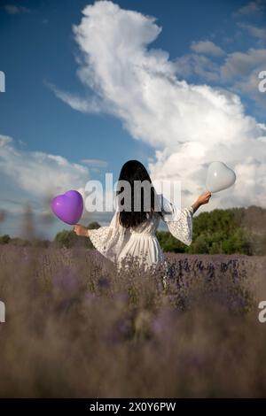 Giovane donna che vagava in un campo di lavanda, con un vestito bianco. Foto Stock