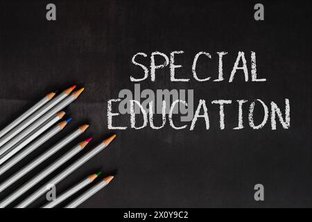 Una lavagna con la parola "educazione speciale" scritta sopra. La lavagna è circondata da una fila di matite, di colori diversi Foto Stock