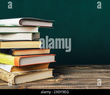 Una pila di libri su un tavolo di legno. I libri sono di diverse dimensioni e colori. La disposizione dei libri crea un senso di ordine e organizzazione Foto Stock