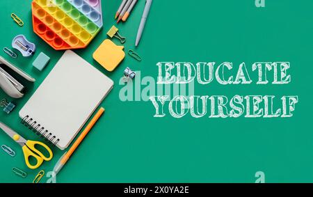 Uno sfondo verde con un quaderno, penne, forbici e una palla da stress. Le parole "educare te stesso" sono scritte in bianco sullo sfondo Foto Stock