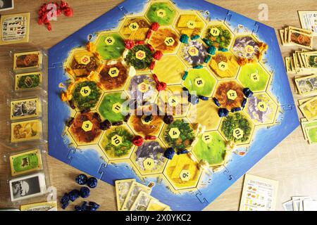 Mozyr, Bielorussia, 01 aprile 2024: Un gioco da tavolo catan è il processo di un gioco a quattro giocatori giallo, rosso, blu, verde componenti, gettoni giocatori sul gioco Foto Stock