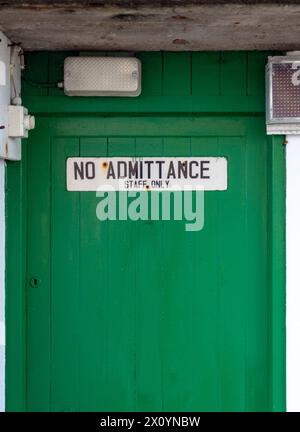 Il personale non ammesso deve firmare solo con lampade e fili elettrici su una porta verde. Foto Stock