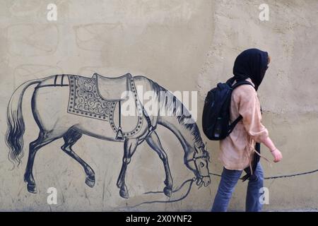 Teheran, Iran. 14 aprile 2024. Una donna iraniana cammina su Karim Khan Street nel centro di Teheran. Domenica Israele ha salutato le sue difese aeree di fronte a un attacco senza precedenti da parte dell'Iran, affermando che i sistemi hanno ostacolato il 99% degli oltre 300 droni e missili lanciati verso il suo territorio. (Credit Image: © Rouzbeh Fouladi/ZUMA Press Wire) SOLO PER USO EDITORIALE! Non per USO commerciale! Foto Stock