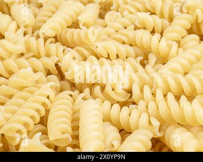 Un mucchio di pasta a spirale fusilli italiana cruda. Sfondo texture. Foto Stock