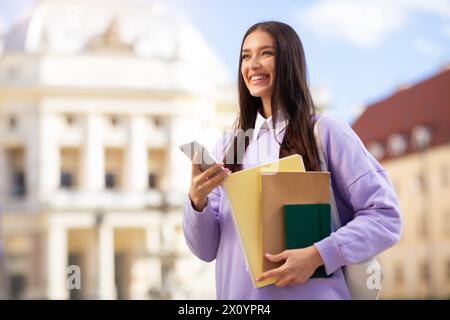 Allegra e bella studentessa che usa uno smartphone Foto Stock