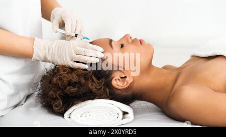 Chirurgia estetica. Donna con iniezione sul fronte Foto Stock