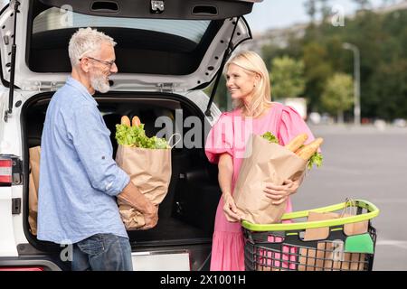 Gli anziani caricano la spesa nel bagagliaio dopo lo shopping Foto Stock