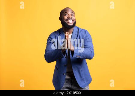 Allegro afroamericano che mette le mani insieme in un gesto di apprezzamento, dicendo grazie. Felice uomo BIPOC che loda gesti di gratitudine, isolato sullo sfondo dello studio Foto Stock