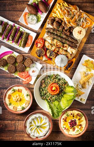 piatti arabi mediterranei dall'alto su un tavolo di legno tabouleh, kibbeh, humus, foglie d'uva ripiene di riso, Foto Stock