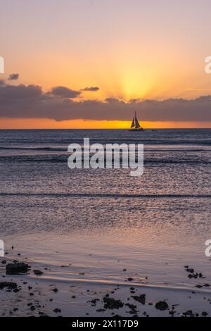 Barca a vela all'orizzonte con il sole che tramonta ad Aruba Foto Stock