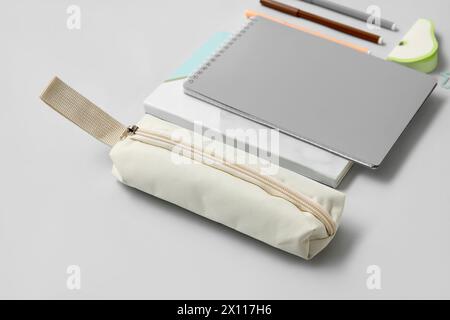 Astuccio beige con cancelleria e quaderni scolastici diversi su sfondo grigio Foto Stock