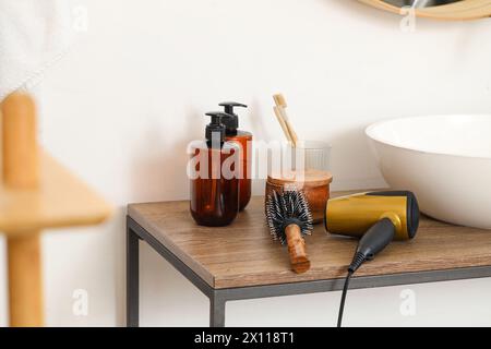 Spazzola rotonda con asciugacapelli sul tavolo in bagno, primo piano Foto Stock