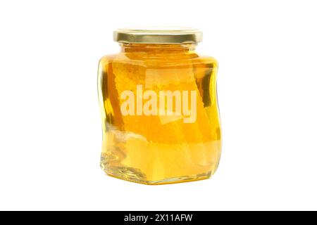 Un vaso di vetro con coperchio dorato contiene miele con favo riempito quasi fino in cima, su sfondo bianco Foto Stock