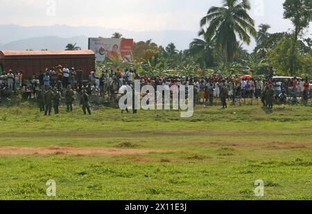 Gli haitiani locali si riuniscono intorno alla zona di atterraggio degli elicotteri, assicurata dai Marines della compagnia Lima, Battalion Landing Team, 3rd Battalion, 2nd Marine Regiment, 22nd Marine Expeditionary Unit a Leogane, Haiti, 20 gennaio 2010. Foto Stock