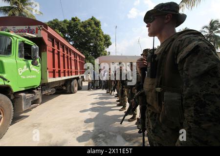 U.S. Marine 1st tenente Gregory Meyer, comandante di plotone con Battalion Landing Team, 3rd Battalion, 2nd Marine Regiment, 22nd Marine Expeditionary Unit, insieme ad altri Marines della BLT forniscono sicurezza per un camion di rifornimento alimentare durante una missione di rifornimento a Leogane, Haiti, 20 gennaio 2010. La missione di approvvigionamento è stata la prima operazione di assistenza umanitaria condotta dal 22° MEU da quando sono arrivati ad Haiti. Foto Stock