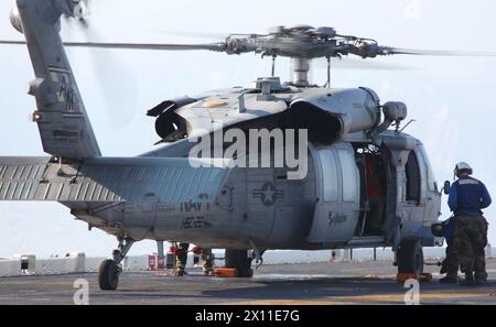 I gestori aerei a bordo della USS Bataan rimuovono i blocchi ruota da un MH-60S Night Hawk della Marina dall'Helicopter Sea Combat Squadron 22, 19 gennaio 2010. La 22nd Marine Expeditionary Unit è imbarcata a bordo delle navi del Bataan Amphibious Ready Group vicino all'isola di Haiti per fornire assistenza umanitaria e soccorsi in caso di disastro in seguito a un devastante terremoto che ha colpito il paese. Foto Stock