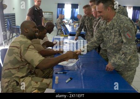 Il sergente Ronald Hartford, un membro del team della cellula di coordinamento delle forze di sicurezza irachene stringe la mano a Israel Idonije, un uomo di linea per i Chicago Bears, in un incontro e saluto presso la Forward Operating base Falcon Dining Facility il 12 aprile. Altri giocatori della National Football League che erano presenti furono Nick Harper, cornerback per i Tennessee Titans, e Chris Harris, safety per i Chicago Bears CA. 2004 Foto Stock