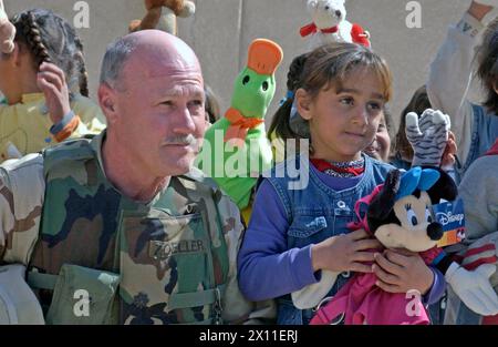 Didascalia originale: Il tenente colonnello Nicholas Zoeller, comandante del 13° comando di supporto agli affari civili, posa con una ragazza irachena che abita il villaggio di Albu Hassan, Iraq. Zoeller ha aiutato a distribuire forniture scolastiche ai bambini iracheni durante l'operazione Iraqi Children, un programma di base fondato dall'attore Gary Sinise e dall'autrice Laura Hillenbrand CA. 18 marzo 2004 Foto Stock