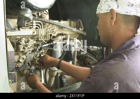CAMP ARIFJAN, Kuwait--Mohammed Alam as Hfaque, dipendente CEB di un paese terzo (TCN), fornisce un servizio di manutenzione sulle attrezzature del CEB, come questo motore generatore CA. 23 giugno 2004 Foto Stock