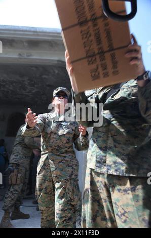 Marines e marinai con Combat Logistics Battalion 22, 22nd Marine Expeditionary Unit, scaricano casi di razioni durante una goccia di cibo e acqua in un sito di distribuzione locale non governativo a Petit Goave, Haiti, 31 gennaio 2010. Foto Stock