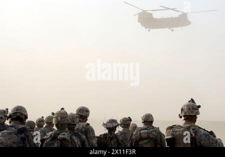 Paracadutisti del 1st Platoon, compagnia C, 1st Battalion, 501st Infantry Regiment, 4th Brigade Combat Team, 25th Infantry Division, guarda come un elicottero CH-47 Chinook inizia la sua decenza durante una tempesta di polvere alla Forward Operating base Kushamond, Afghanistan, in preparazione per una missione di assalto aereo CA. 7 settembre 2004 (i metadati riportano l'anno 2009) Foto Stock