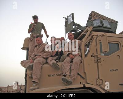 Il sergente Charlie Brown (seduto all'estrema sinistra), uno specialista di rete dati del 2nd Marine Logistics Group (avanti), posa per una foto con la 3rd Machine Gun Squad, Weapons Platoon, Kilo Company, 3rd Battalion, 1st Marine Regiment, durante il loro dispiegamento in Iraq nel 2005. Brown è stato premiato con due Purple Heart Medals per le ferite ricevute in azione lo stesso giorno durante il suo dispiegamento. ca. 2005 Foto Stock