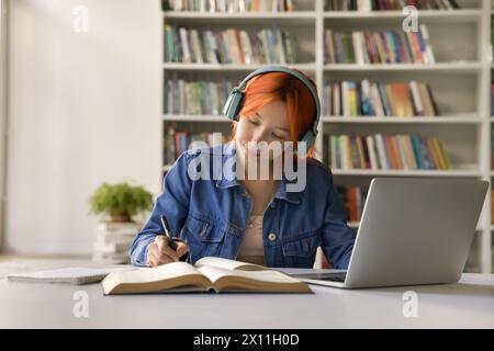 Studentessa dei 17 anni con i capelli rossi concentrata che fa il lavoro scolastico Foto Stock