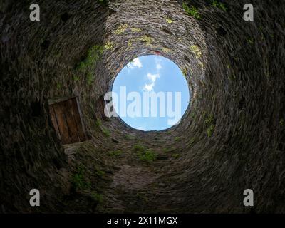 Pozzo in pietra, vecchia costruzione dall'interno, pareti in mattoni e sfondo blu cielo, cadono nel concetto di pozzo Foto Stock