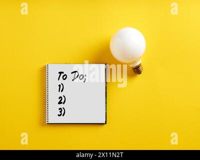 Per eseguire l'elenco di controllo sul blocco note con una lampadina. Elenco delle attività, attività da completare per il progetto o il concetto di piano aziendale. Foto Stock