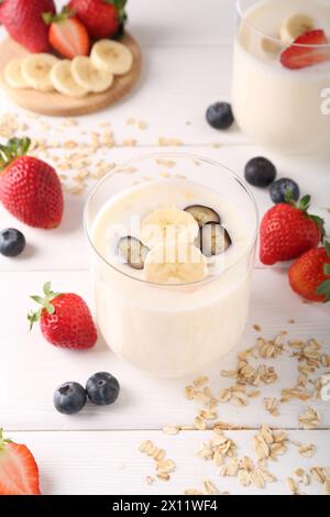 Pausa salutare. Composizione con gustoso yogurt, banana e frutti di bosco in bicchieri su tavolo di legno bianco Foto Stock