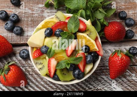 Gustosa Macedonia di frutta nel recipiente e ingredienti su un tavolo di legno, in piano Foto Stock