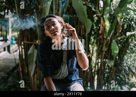 un uomo che stava bruciando la sigaretta in una zona di alberi ​​dense Foto Stock