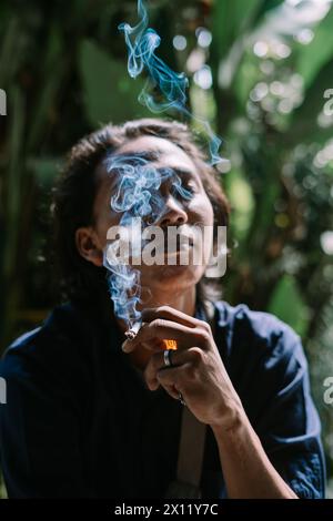 un uomo che stava bruciando la sigaretta in una zona di alberi ​​dense Foto Stock