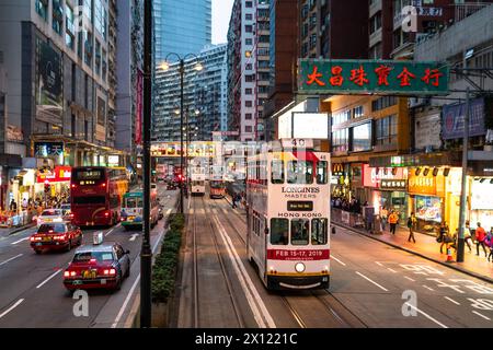 North Point, Hong Kong - 15 marzo 2019: Un tram a due piani attraversa l'affollato quartiere di North Point al crepuscolo sull'isola di Hong Kong, in Cina Foto Stock