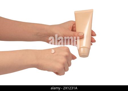 Tubo di crema beige in mani di donna isolate su sfondo bianco. Campione di crema sulla mano della donna. Concetto di cura della pelle. Foto Stock