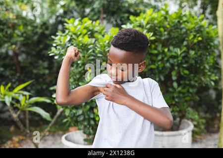 Ragazzo afroamericano che mostra i muscoli, nel cortile di casa Foto Stock