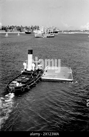 Taveta Tug o Tugboat che lavorano nel porto, nel porto o nel porto di Mombasa, Kenya. Vintage o storico monocromatico o bianco e nero immagine c1960 Foto Stock