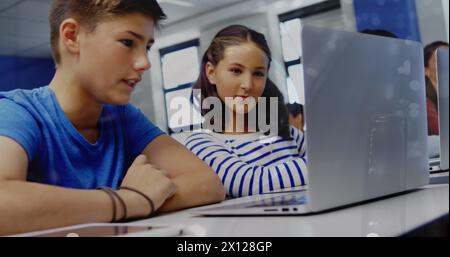 Immagine dell'elaborazione dei dati finanziari e del globo su scolari diversi che utilizzano laptop in classe Foto Stock