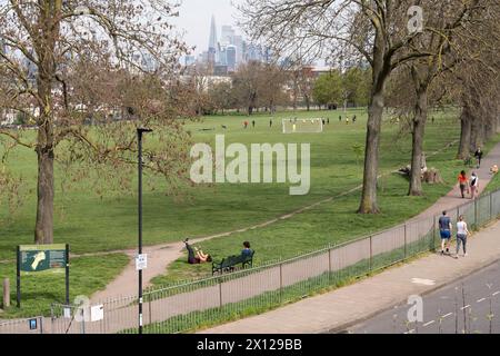 Mentre un corridore si allunga, altri londinesi del sud godono dello spazio verde pubblico di Ruskin Park il sabato mattina, il 13 aprile, a Lambeth, sud di Londra, Inghilterra. Foto Stock